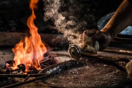 Traditional Turkish tinsmith, crafting over open flame.