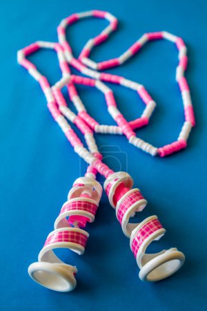 Photo for Loosely laid pink and white toy jump rope on blue background. - Royalty Free Image