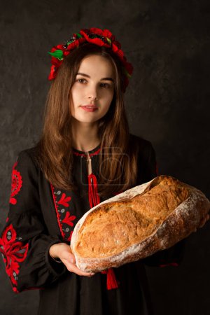 Téléchargez les photos : Une femme ukrainienne dans une robe brodée et une couronne tient une palyanitsa ukrainienne dans ses mains - en image libre de droit