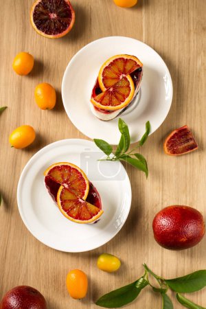 Foto de Postre Panna cotta con gelatina de bayas y naranja roja en un plato blanco - Imagen libre de derechos