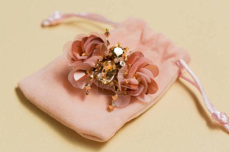 Decorative handmade brooch in the shape of a beetle on a plush bag on a beige background