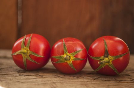 Photo for Whole tomatoes on brown textured wood - Royalty Free Image