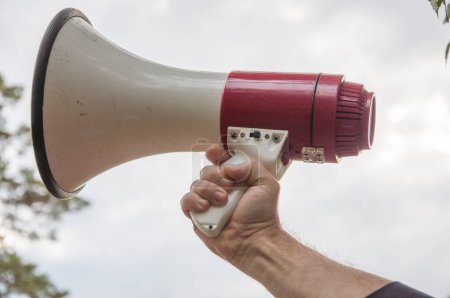 Photo for Megaphone in activist, leader's hand. Prepare to announce. concept : equipment for speaking to make louder in outdoor activities, camping, protesting, parade campaign or playing games. - Royalty Free Image