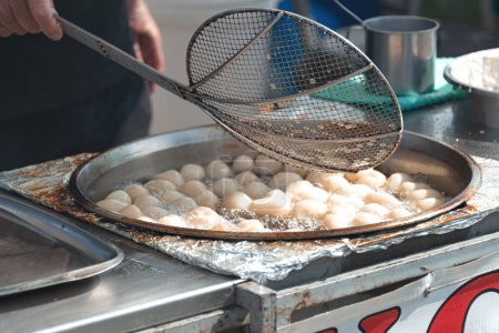 Cook is preparing a Loukoumades dough balls in boiling oil. Cyprus
