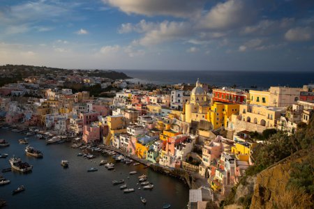 View of the Port of Corricella with lots of colorful houses in the sunset, Procida Island, Italy.