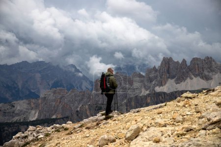 Hombre excursionista con mochila en la colina disfrutando de pintoresca vista de los Alpes Dolomitas cerca de Rifugio Nuvolau, Italia. Gente activa y concepto de montaña.