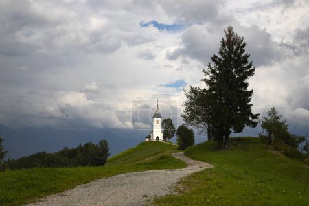 Jamnik, Slowenien. Die Kirche Jamnik ist eine bezaubernde Kapelle aus dem 15. Jahrhundert in den Kamnik-Savinja-Alpen in der Nähe von Kranj, mit atemberaubender Aussicht auf die umliegende Berglandschaft.