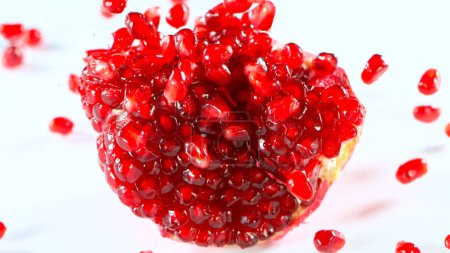 Photo for Fresh pomegranate pieces falling, white background - Royalty Free Image
