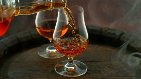 Foto de Close-up of pouring whiskey or rum on old wooden barrel - Imagen libre de derechos