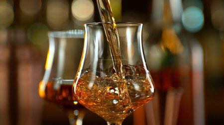 Téléchargez les photos : Close-up of pouring whiskey or rum on the bar, dark toned background - en image libre de droit