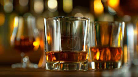 Téléchargez les photos : Close-up of pouring whiskey or rum on the bar, dark toned background - en image libre de droit