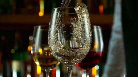 Téléchargez les photos : Close-up of pouring white wine on the bar, dark toned background - en image libre de droit