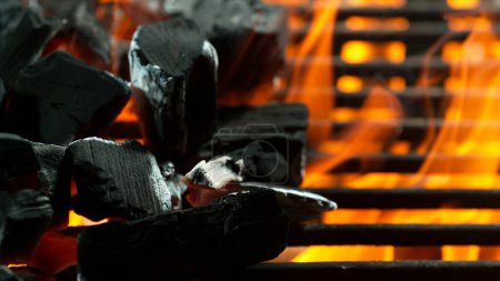 Téléchargez les photos : Prise de vue de mouvement de gel de charbon de bois brillant sur le barbecue de jardin, prise de vue macro - en image libre de droit