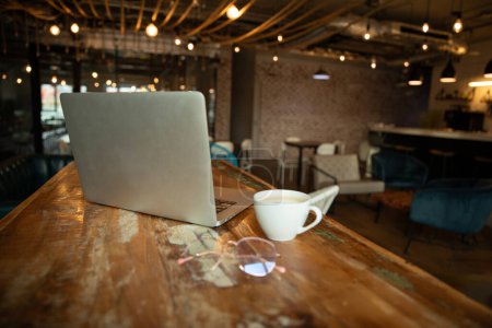 Téléchargez les photos : Espace de travail avec ordinateur portable moderne et tasse de café, gros plan - en image libre de droit