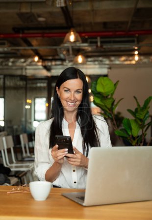 Téléchargez les photos : Femme d'affaires travaillant sur ordinateur portable tout en étant assis au bureau sur le lieu de travail. Femme comptable confiante en costume travaillant dans un bureau moderne - en image libre de droit