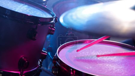 Photo for A drummer plays on a dark stage in the fog and neon lights. - Royalty Free Image