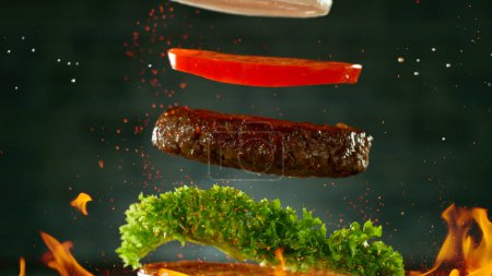 Foto de Hamburguesa de carne con ingredientes Caída y aterrizaje en el pan - Imagen libre de derechos