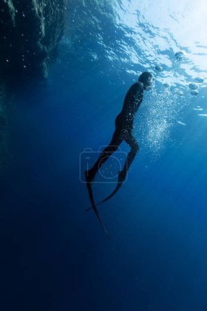 Photo for Freediver Swimming in Deep Sea With Sunrays. Young Man DIver Eploring Sea Life. - Royalty Free Image