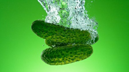 Téléchargez les photos : Congeler le mouvement des concombres frais qui tombent dans l'eau - en image libre de droit