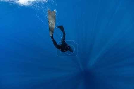 Foto de Freediver Natación en aguas profundas con rayos de sol. Joven bricolaje Eploring Sea Life. - Imagen libre de derechos