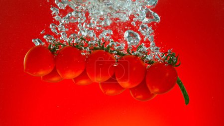 Photo for Freeze motion of falling fresh cherry tomatoes into water - Royalty Free Image