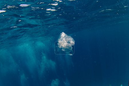 Téléchargez les photos : Sac plastique flottant sous l'eau sur la profondeur bleue, pollution de l'environnement. Pollution plastique de l'océan - en image libre de droit