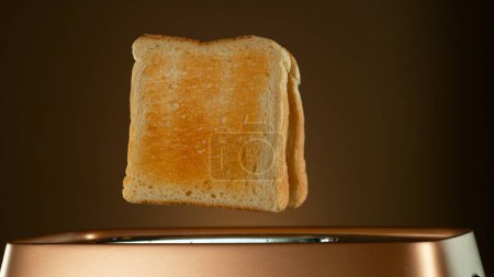 Photo for Crispy Golden Toasts Jumping out of Toaster on Bronze Gradient Background - Royalty Free Image