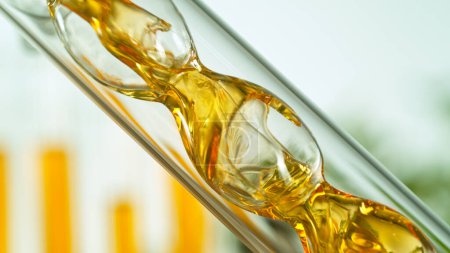 Téléchargez les photos : Obtenir de l'huile naturelle à partir de substances naturelles et fleurs. Flux d'huile jaune en spirale. - en image libre de droit