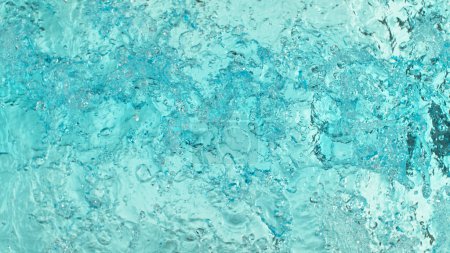 Téléchargez les photos : Gros plan sur les éclaboussures de surface de l'eau sur fond bleu clair - en image libre de droit