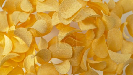 Téléchargez les photos : Congeler le mouvement des chips de pommes de terre frites volantes sur fond jaune - en image libre de droit