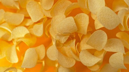 Photo for Freeze motion of flying fried potatoes chips on yellow background - Royalty Free Image