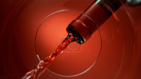 Photo for Freeze Motion Shot of Red Wine Pouring, Unique Angle of View from the Bottom of the Glass - Royalty Free Image