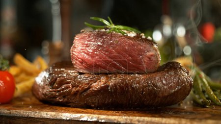 Téléchargez les photos : Vue d'un steak de bœuf frais sur une planche de bois placée sur le comptoir de la cuisine. Le concept de préparation de la viande. - en image libre de droit