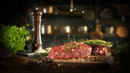 Foto de El primer plano de la sal que cae sobre el bistec sabroso de carne en la cocina. - Imagen libre de derechos