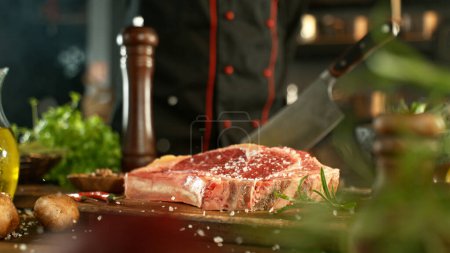 Téléchargez les photos : Vue d'un steak de bœuf cru frais sur une planche de bois placée sur le comptoir de la cuisine. Le concept de préparation de la viande. - en image libre de droit