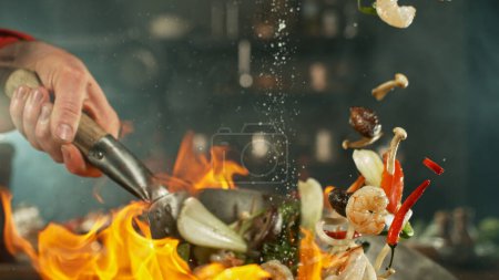 Téléchargez les photos : Congeler le mouvement des nouilles de wok asiatiques volantes avec des prans et des légumes. Le concept de préparation de la viande. - en image libre de droit