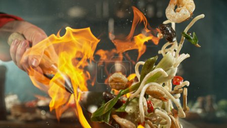 Téléchargez les photos : Congeler le mouvement des nouilles de wok asiatiques volantes avec des prans et des légumes. Le concept de préparation de la viande. - en image libre de droit