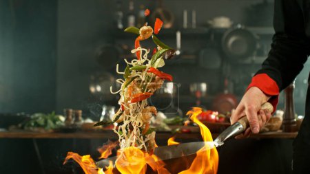 Foto de Congelar el movimiento de volar fideos wok asiáticos con prans y verduras. El concepto de preparación de la carne. - Imagen libre de derechos