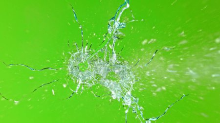 Foto de Primer plano del disparo a través del vidrio, rompiendo contra el fondo verde - Imagen libre de derechos