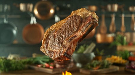 Téléchargez les photos : Gros plan d'un délicieux steak de boeuf volant au-dessus d'une grille en fonte avec des flammes de feu - en image libre de droit