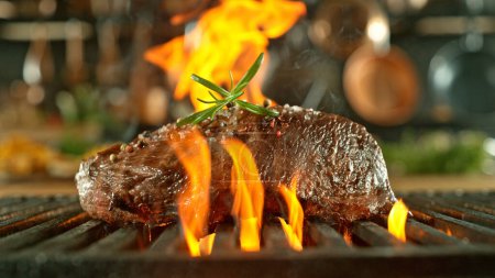 Téléchargez les photos : Gros plan de délicieux steak de boeuf cru sur une grille en fonte avec des flammes de feu - en image libre de droit