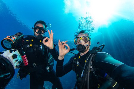 Téléchargez les photos : Plongeurs sous-marins nageant en haute mer avec des rayons de soleil. Jeune homme plongeur déplorant la vie en mer. - en image libre de droit