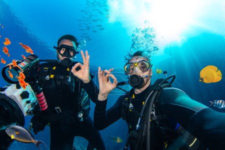 Téléchargez les photos : Plongeurs sous-marins nageant en haute mer avec des rayons de soleil. Jeune homme plongeur déplorant la vie en mer. - en image libre de droit