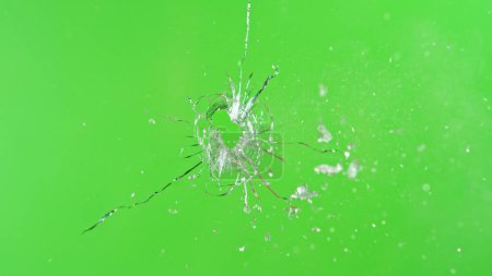 Téléchargez les photos : Gros plan du coup de feu dans le verre, brisant sur le fond vert - en image libre de droit