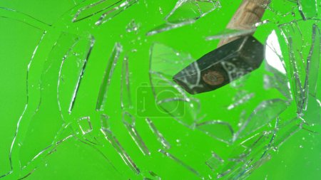 Téléchargez les photos : Mouvement de gel du marteau brise-verre, brisant sur fond vert - en image libre de droit