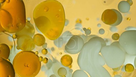 Inyección de movimiento de congelación de burbujas de aceite y leche en movimiento sobre fondo dorado, concepto de cosméticos