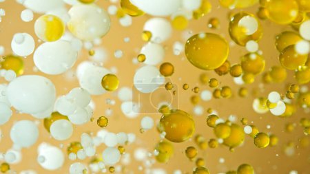 Foto de Inyección de movimiento de congelación de burbujas de aceite y leche en movimiento sobre fondo dorado, concepto de cosméticos - Imagen libre de derechos