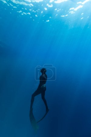 Freitaucher schwimmen in der Tiefsee mit Sonnenstrahlen. Junger Mann beschwert sich über das Leben im Meer.