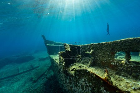 Photo for Freediver Swimming in Deep Sea With Sunrays. Young Man Diver Eploring Shipwreck - Royalty Free Image