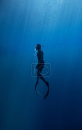 Photo for Freediver Swimming in Deep Sea With Sunrays. Young Man Diver Eploring Sea Life. - Royalty Free Image